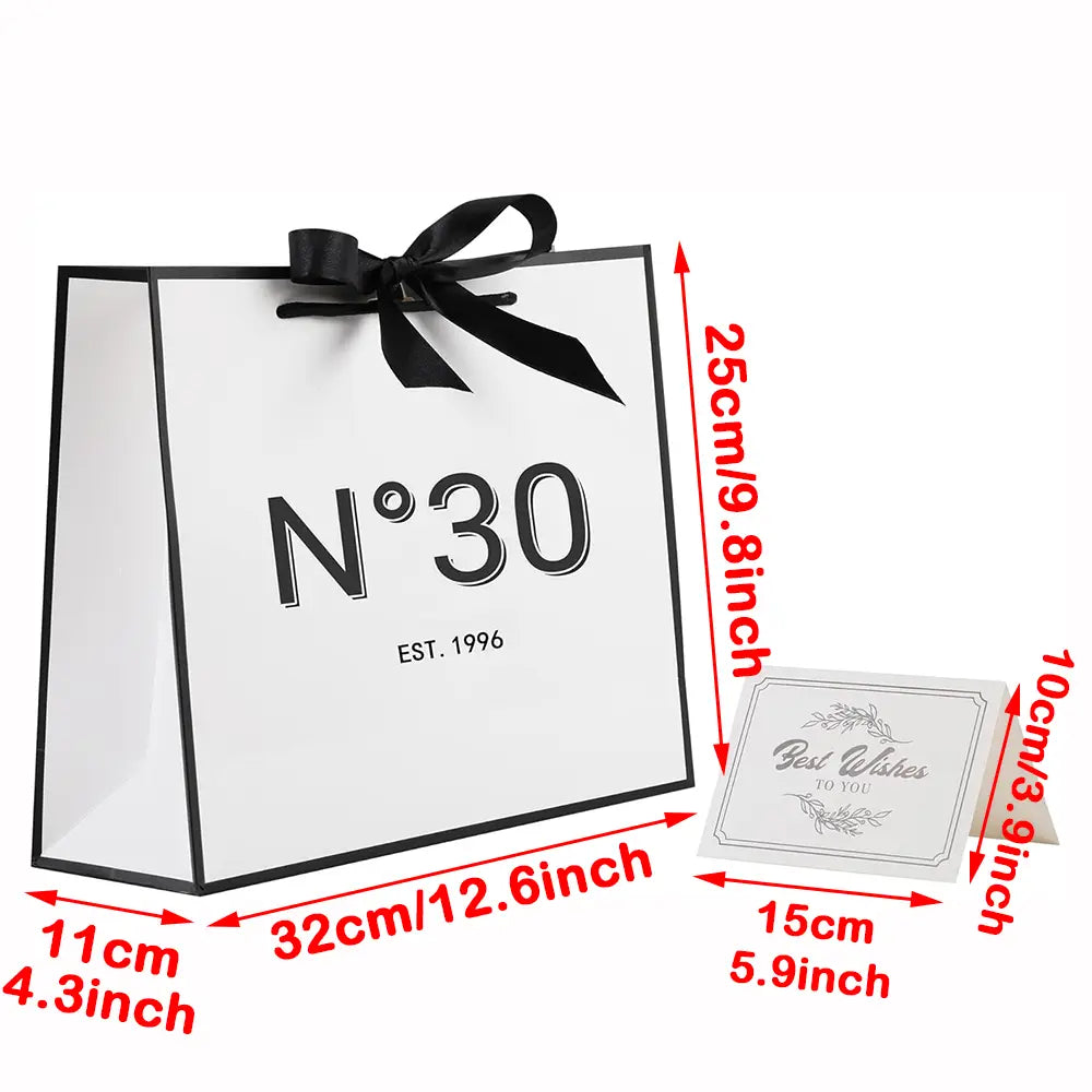 Tragetasche aus weißem Papier mit schwarzem Rand und schwarzer Satin-Schleifenborte mit n°30 in der Gestaltung als Geschenk zum runden Geburtstag mit Karte und Schleife.