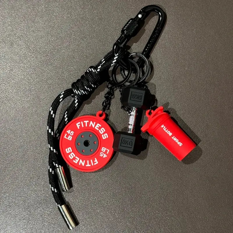 Porte-clés de musculation rouge et noir comprenant un disque de poids circulaire, une mini-breloque d’haltère et une breloque de bouteille shaker, conçu comme accessoire de cadeau de fitness.