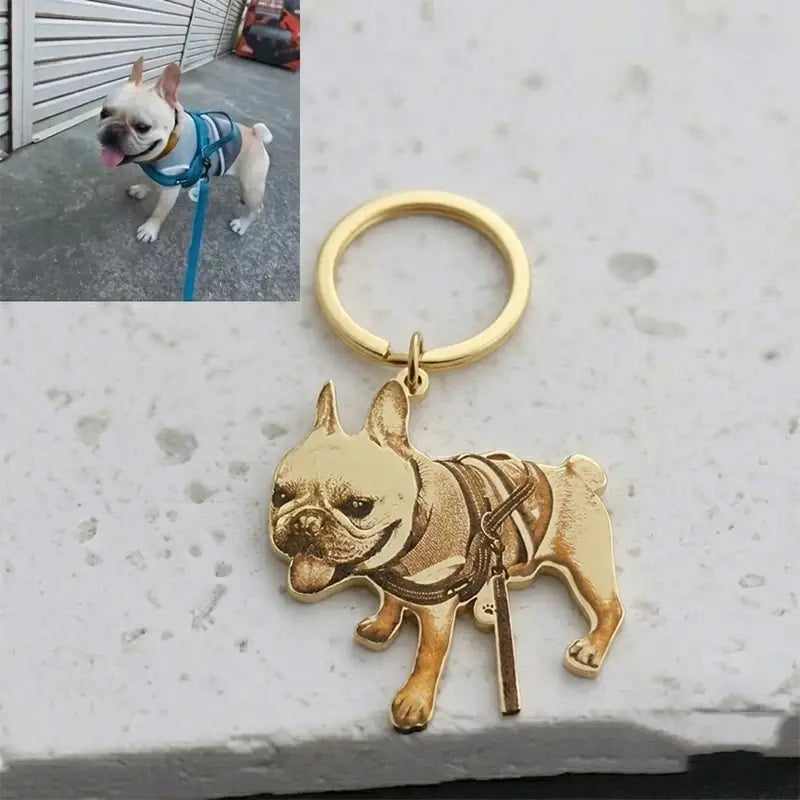 Gold-colored stainless steel keychain featuring a custom photo engraved detailed portrait of a French bulldog wearing a harness and leash.