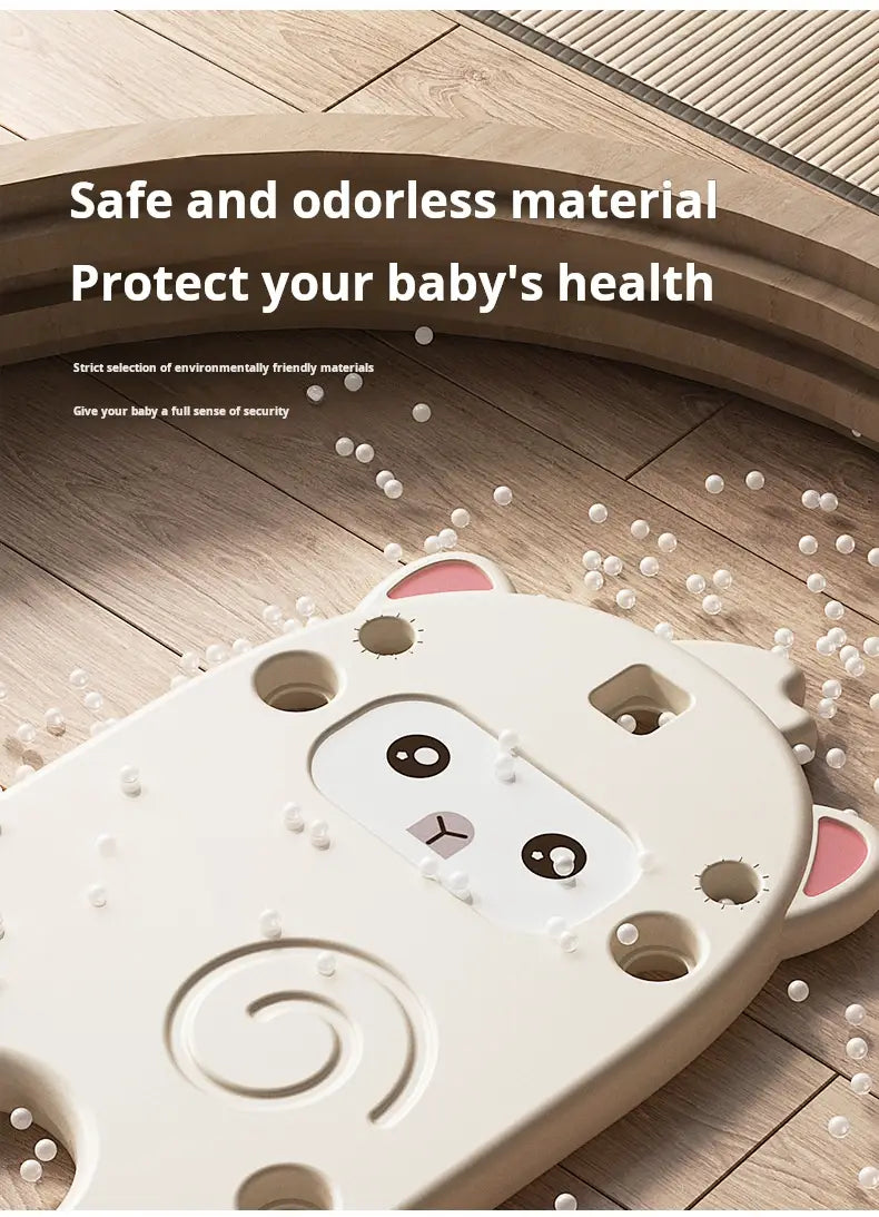 tapis d’activité pour bébé en plastique blanc, avec des détails d’oreille interne roses et des yeux circulaires noirs, présentant un design en spirale affiché avec un porte-jouets multi-étages en plastique pour ranger les jouets des enfants
