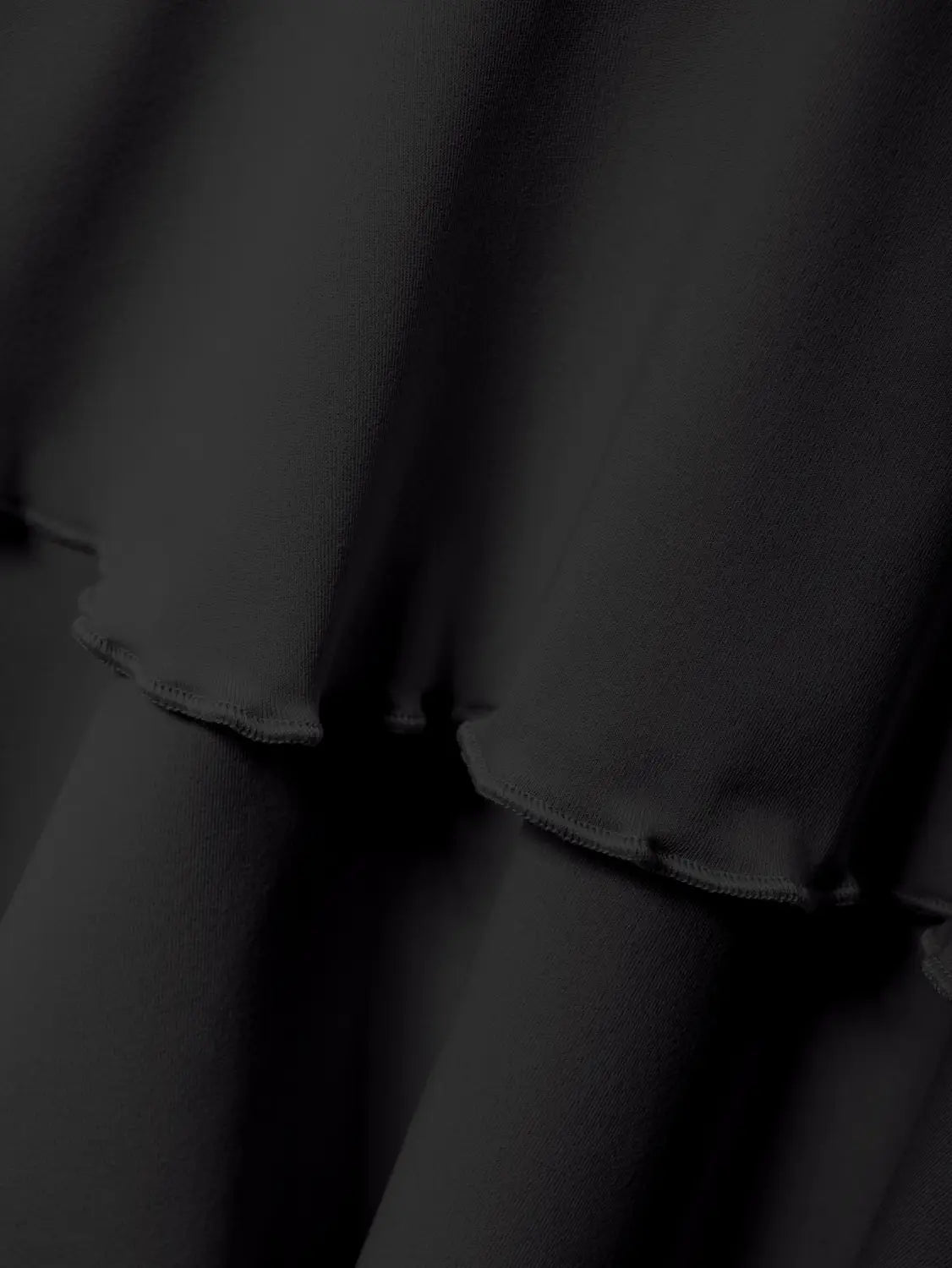 Black high waist ruffle mini skirt made of soft flowing black ruffled fabric showcasing texture and design.