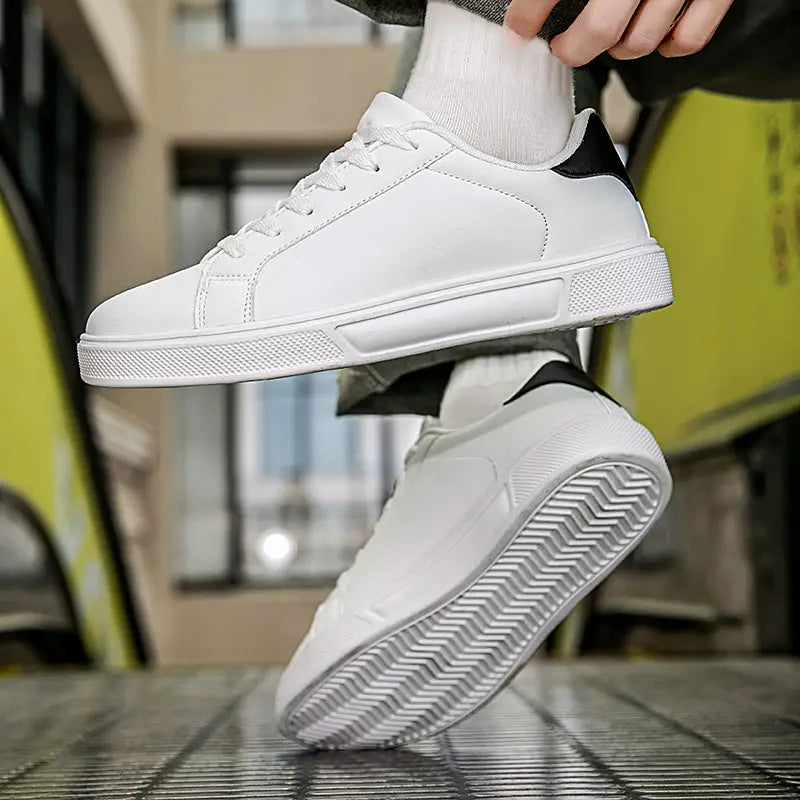 Weiße Ledersneaker im Freizeitstil bieten ein klares Low-Top-Design mit schwarzen Akzenten an der Ferse und der Zunge sowie einer strukturierten Gummisohle für sportliche Leichtgewichtsanwendungen.