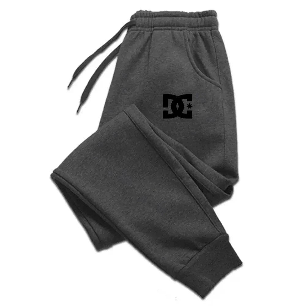 Dunkelgraue Dc Shoes Herren-Jogginghosen mit schwarzem Logo auf dem linken Oberschenkel, entworfen als legere Sweatpants.