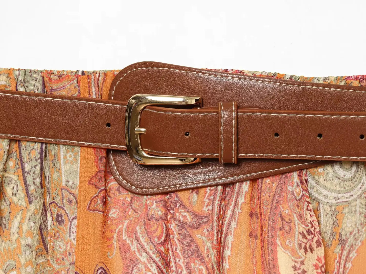 Ceinture marron en cuir à boucle ton or et surpiqûres blanches, assortie à la jupe midi taille haute à imprimé cachemire.