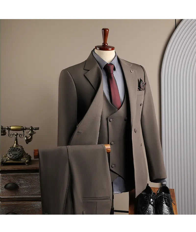 Ensemble trois pièces costume d’affaires pour homme gris anthracite slim fit, confectionné avec précision, avec veste à revers cranté double boutonnage et gilet assorti, porté sur une chemise habillée bleu clair, pour les occasions d’affaires en mode masculine et de soirées décontractées.