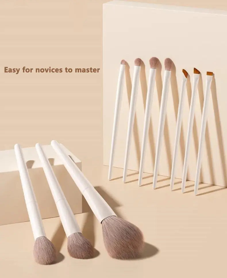 Ensemble de douze pinceaux de maquillage à manches blancs, aux poils taupe doux, disposés avec soin dans une présentation minimaliste pour une utilisation cosmétique
