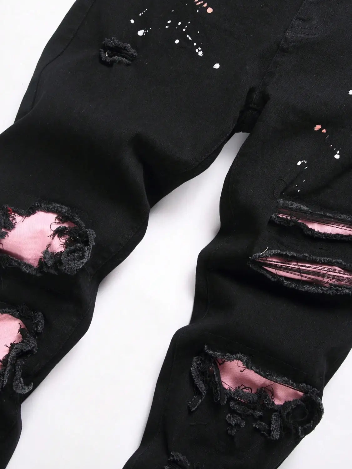 Jeans denim skinny extensibles déchirés Y2K pour hommes en noir, denim délavé, avec une doublure intérieure rose et des accents d’éclaboussures de peinture blanche