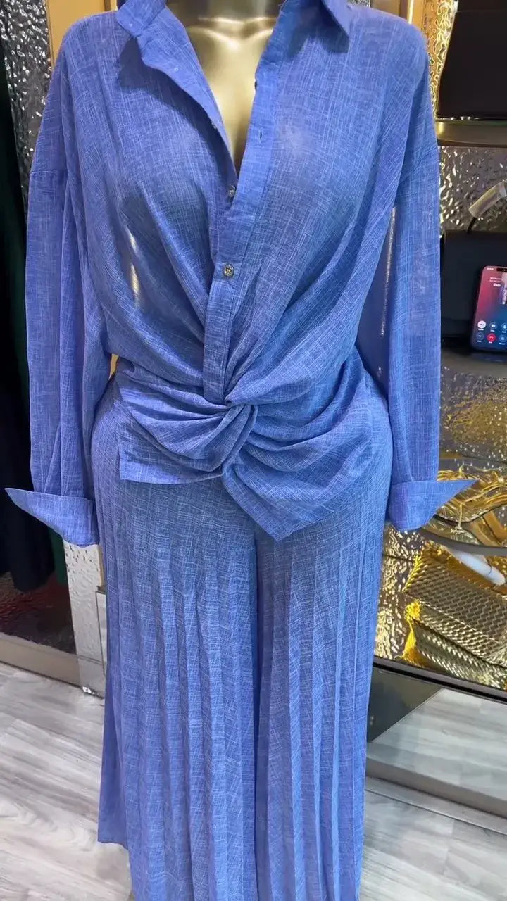 Ein blaues strukturiertes Leinenhemd mit Knopfverschluss und vorderem Knotendetail, kombiniert mit Damen-Hosen im weitem Bein im Falten-Design in einem langärmeligen Outfit.