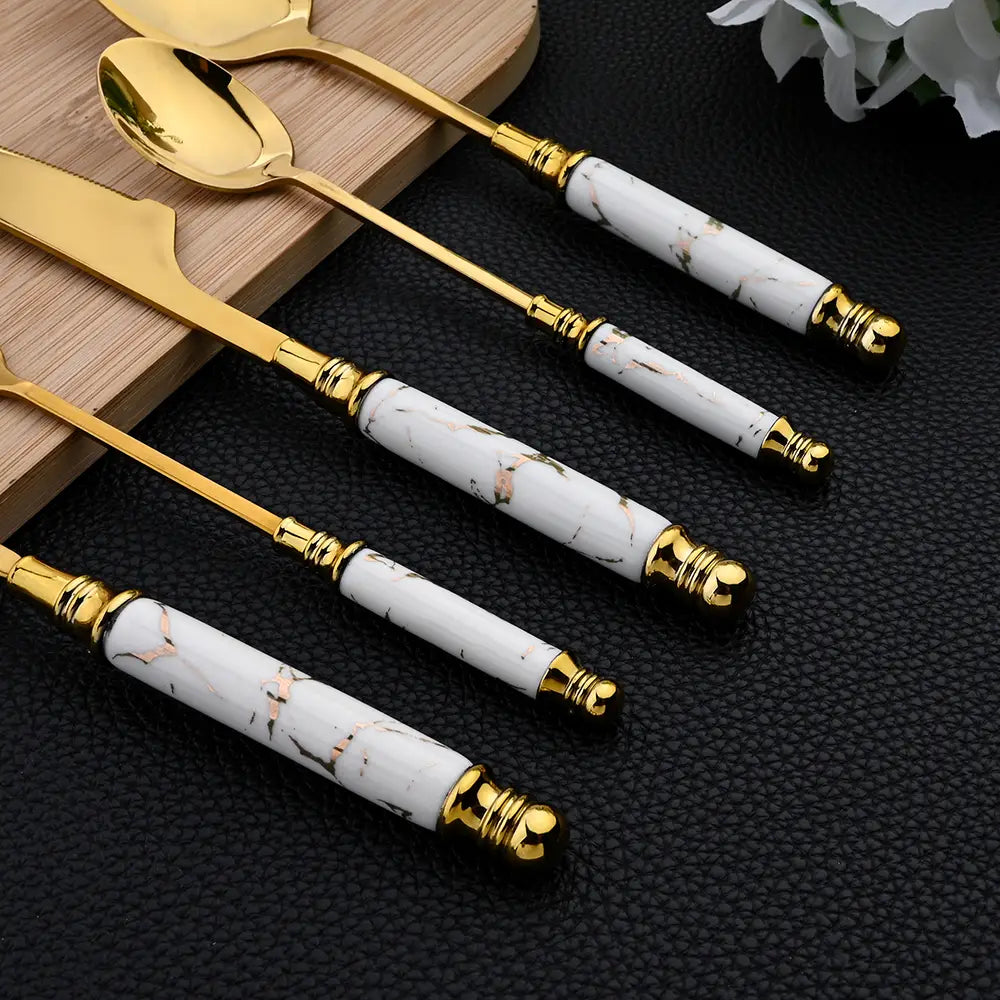 Juego de cubiertos de acero inoxidable con mármol dorado elegante de 16 piezas, con mangos de mármol blanco con detalles en oro y vetas en tono oro rosa.
