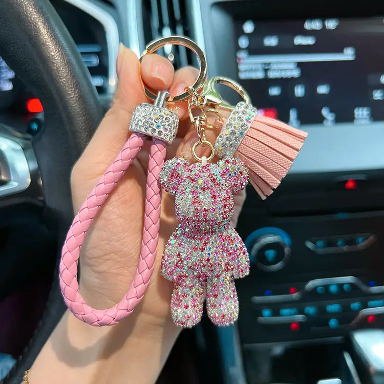 Pink braided leather keychain with a rhinestone-encrusted bear charm and matching tassel for stylish accessory organization.