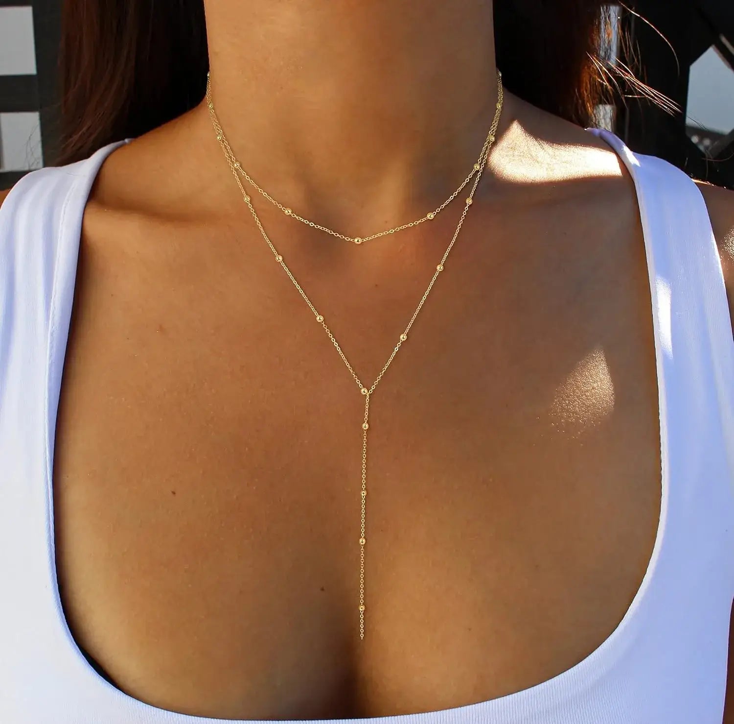 Collier en couches d’or en forme de y pour femmes, présentant une chaîne délicate au ton or avec de petites perles sphériques.