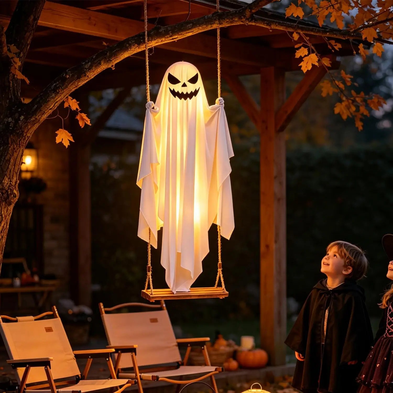 Una decoración de columpio de árbol de Halloween con fantasma colgante blanco y brillante, colgada de una rama de árbol en un columpio de árbol de madera de 47 pulgadas, iluminada con luz cálida.