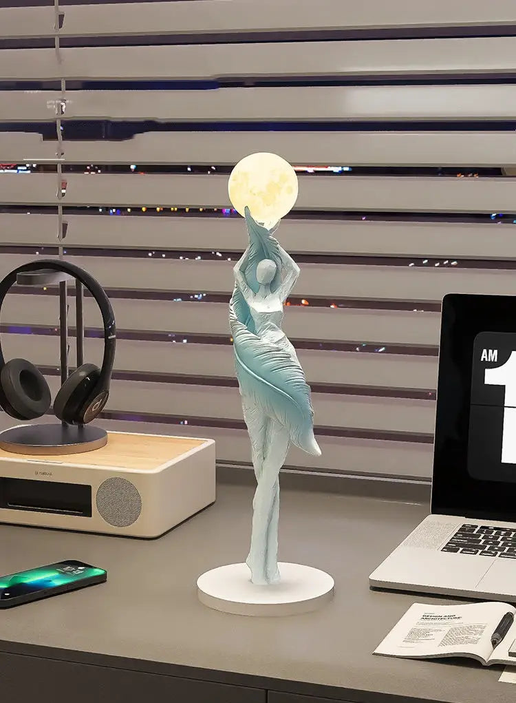 Une délicate figurine de danseuse en résine bleu clair 12x12x40 cm tenant une sphère lumineuse sur une base circulaire blanche, conçue pour une décoration intérieure moderne et des effets d'exposition.