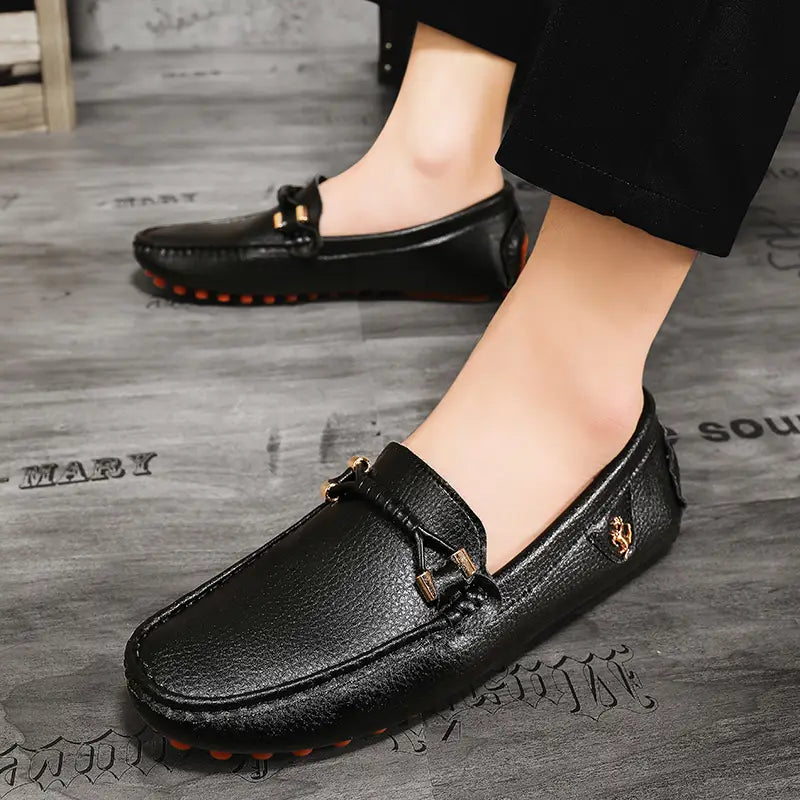 Chaussures à enfiler habillées en cuir noir pour hommes, avec des accents métalliques ton or et une surface texturée, conçues pour un port décontracté sans effort.