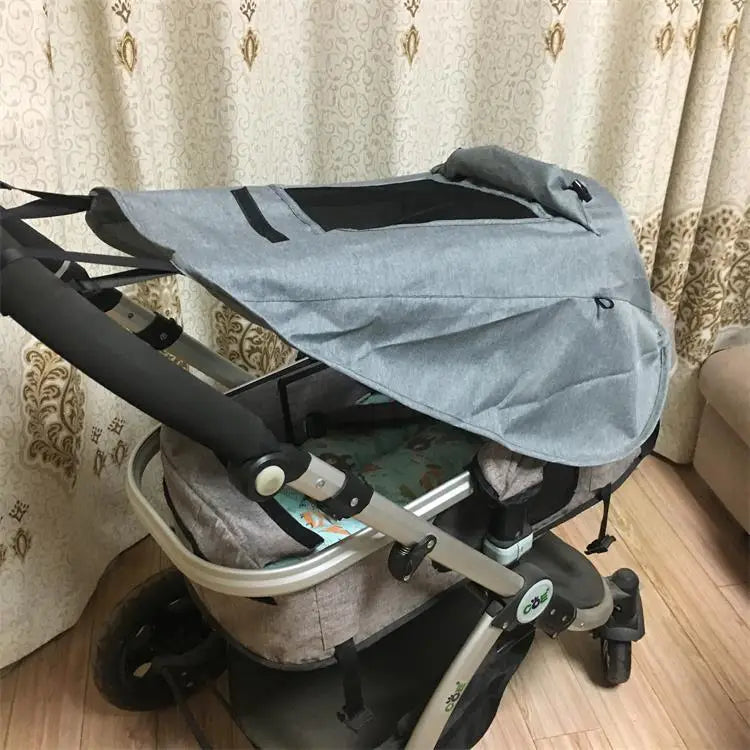 Graues Stoff-Sonnensegel mit schwarzem Besatz, das den Sitzbereich eines Universalkinderwagen-Sonnensegels mit UV-Schutz abdeckt.