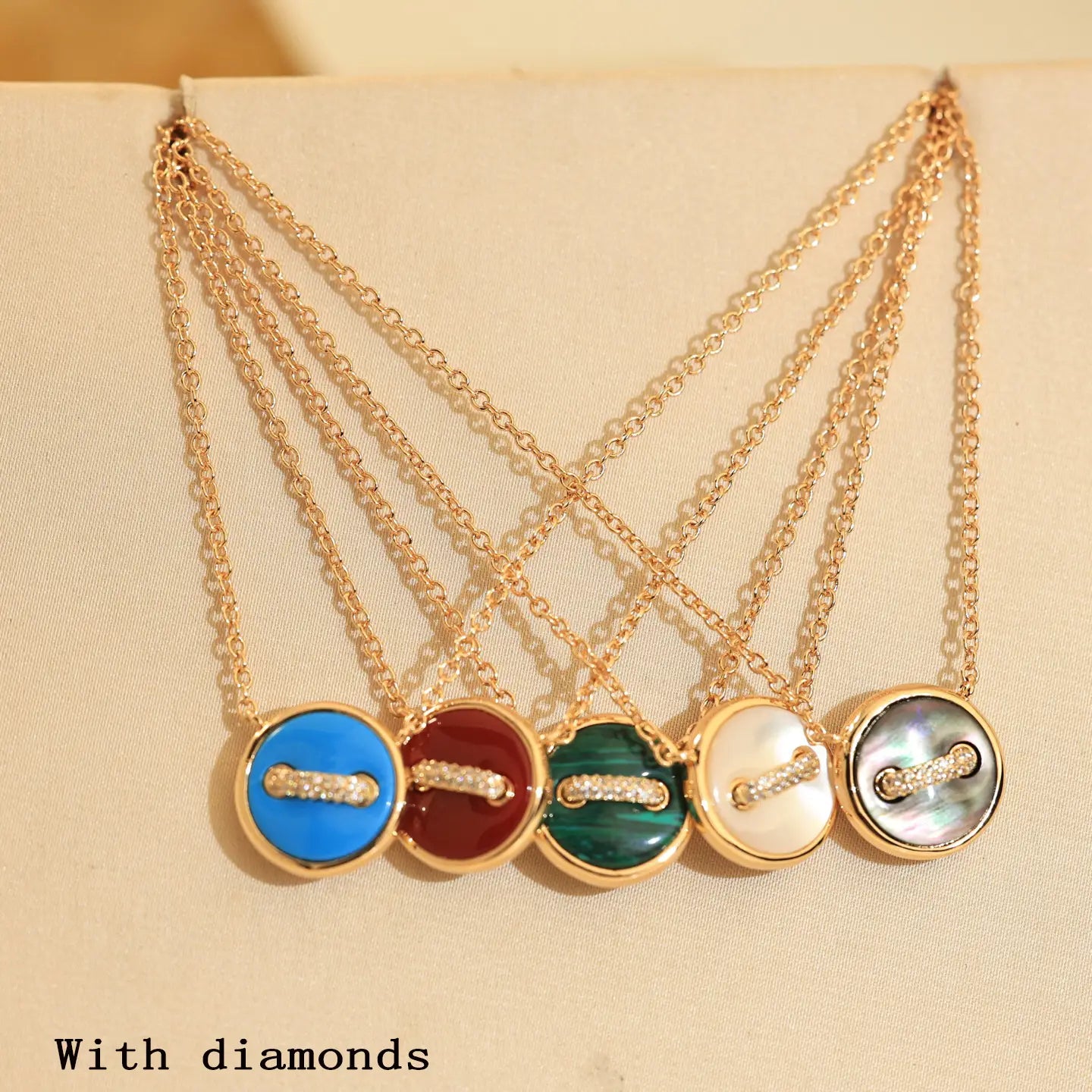 Collier bouton double plaqué en or rose, présentant cinq pendentifs de style bouton ton sur ton, avec des faces émaillées colorées en bleu, rouge, vert, blanc, nacre et coquille nacrée irisée, ainsi qu’une barre sertie de diamants au centre en argent sterling.