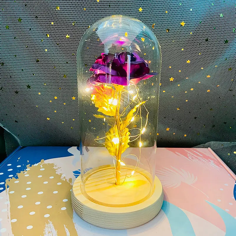 Geschenk „Eternal Gold Rose Glass Dome LED Light“, mit einer violetten und goldenen konservierten Rose, mit integrierten Feenlichtern, im Inneren einer klaren Glaskuppel auf einem Holzsockel.