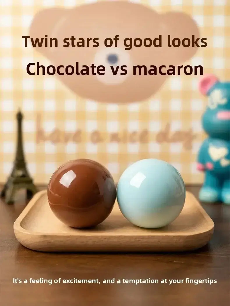 Dos juguetes sensoriales antiestrés tipo pelota esférica brillante y crujiente, en tonos marrón oscuro y azul pastel suave, que imitan golosinas de chocolate y macarrón.