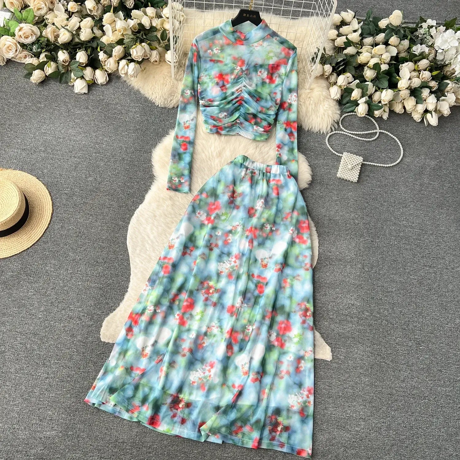 a two-piece mesh skirt set in marble print featuring a high-neck long-sleeved top with ruched detailing and a flowing maxi skirt in pastel blue, green, red, and white with an elastic closure type.