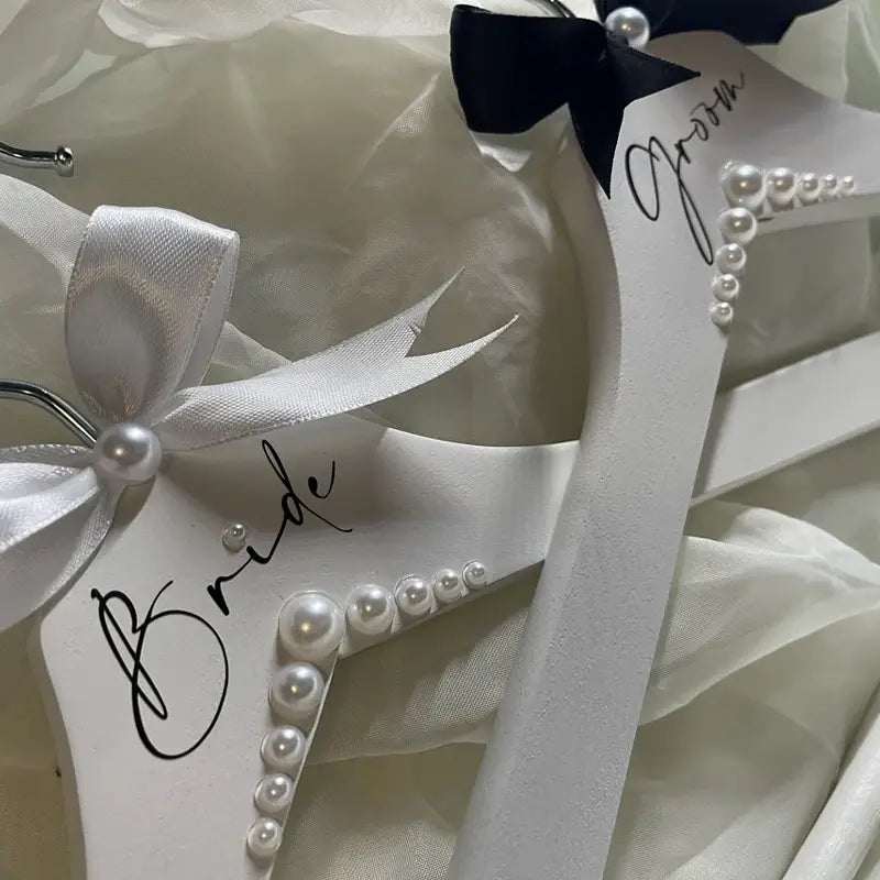 Ensemble de cintres de mariage en bois blanc ornés de perles et de nœuds en satin, étiquetés « mariée » et « marié » dans l’ensemble de cintres de mariage pour la mariée et le marié en perles.