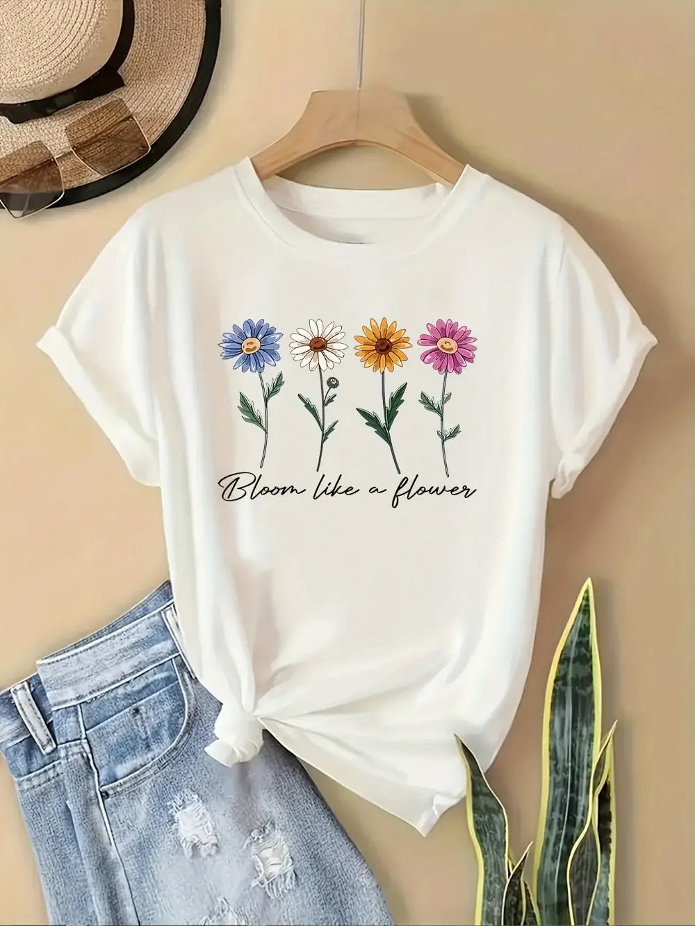 camiseta casual de manga corta de algodón blanco con estampado floral, que incluye un diseño floral colorido con la frase bloom like a flower impresa debajo.