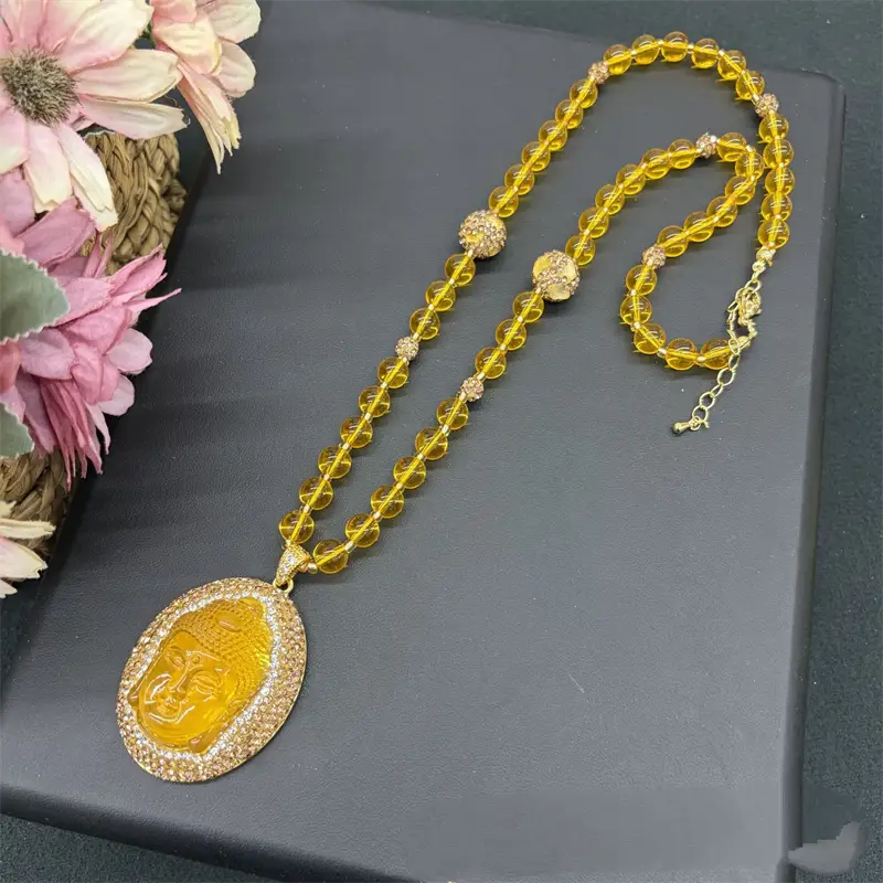 Collier de pendentif Bouddha doré, avec des perles de couleur ambre et des accents étincelants en cristal sur une chaîne à perles ornée de strass, adapté à divers groupes d’âge applicables et compatible avec des fermoirs à pince en forme de sésame.
