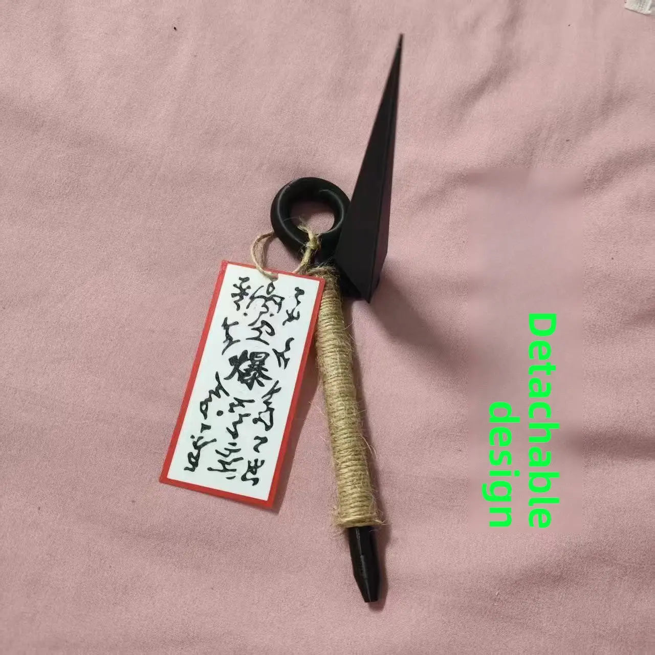 Kühlschrankmagnet aus schwarzem Kunststoff in Form eines Ninja-Kunai mit seilumwickeltem Griff und einem aus PVC gefertigten, rot eingefassten Schild, das befestigt ist.