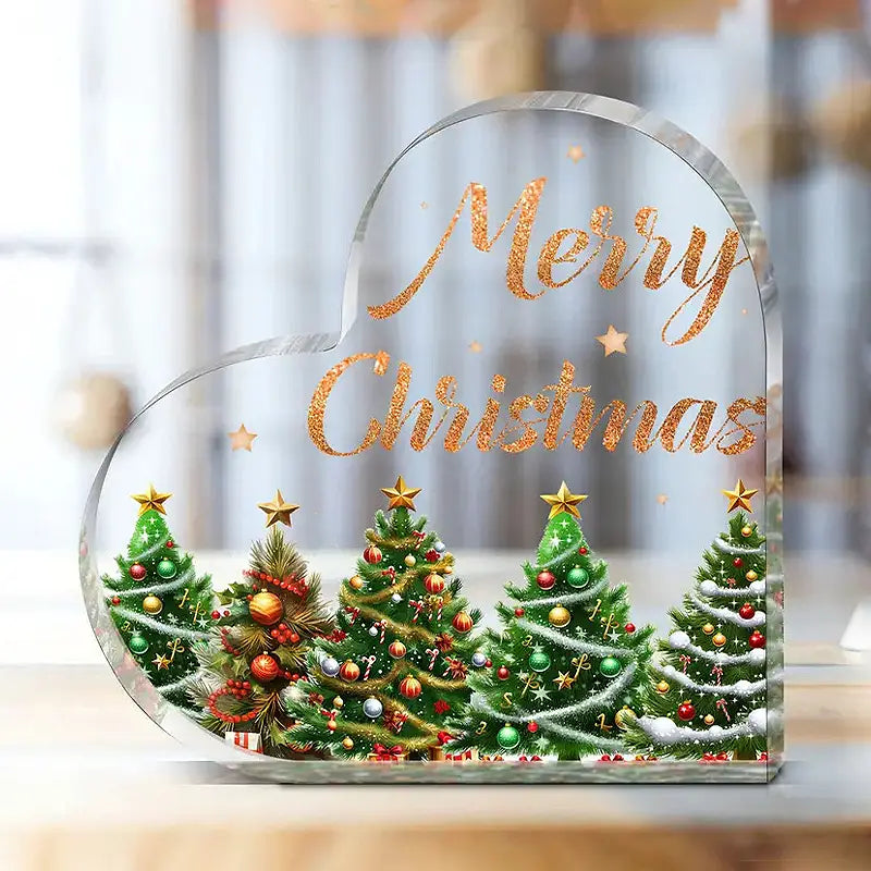 Soporte para adorno de escritorio en forma de corazón navideño de acrílico transparente y claro, con forma de nube, que presenta texto de “Feliz Navidad” en dorado brillante y cinco pinos verdes decorados con adornos y estrellas.