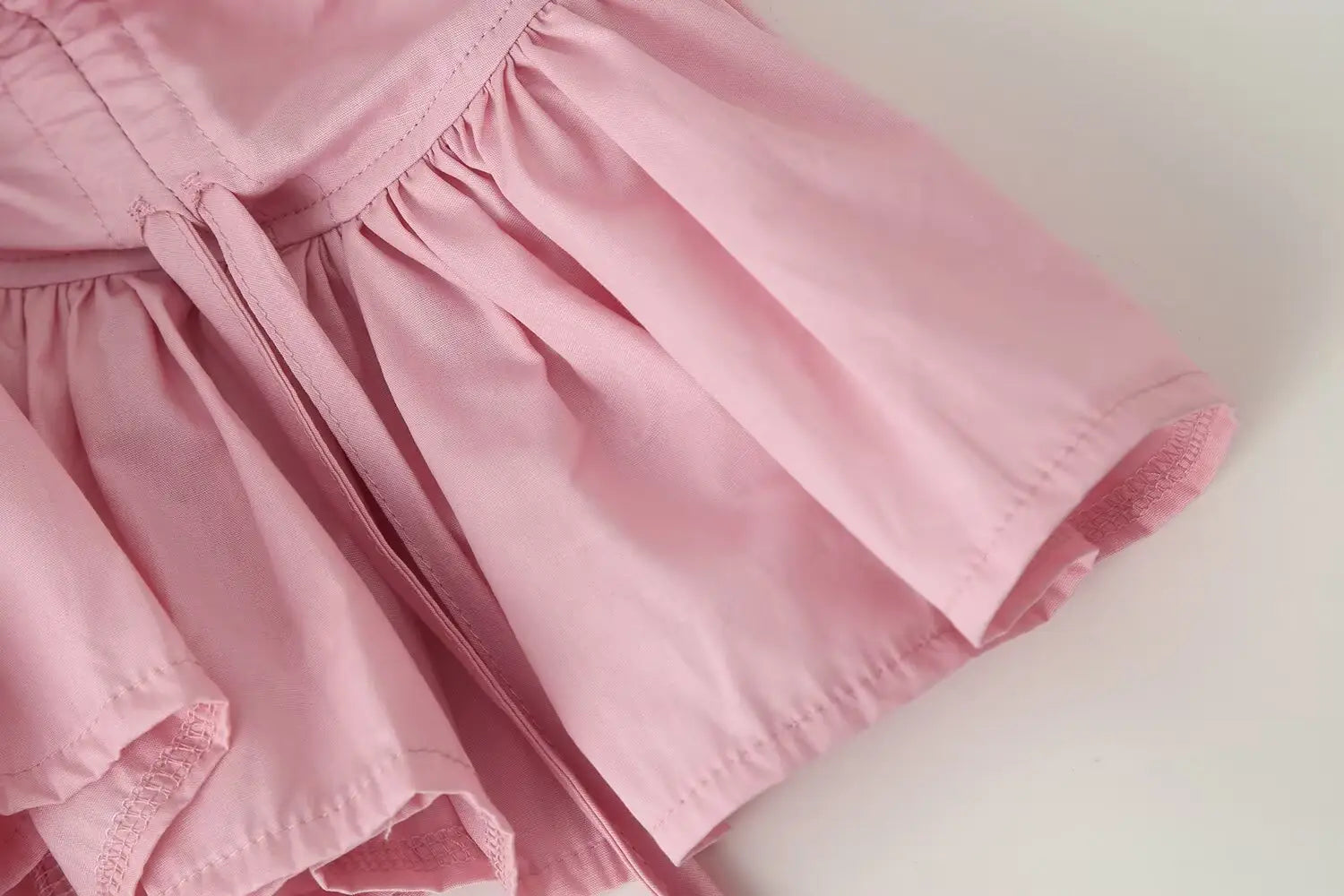 a soft pink lightweight fabric skirt with a gathered waist and ruffled hem paired with a women slim-fit design long sleeve top featuring a round neckline