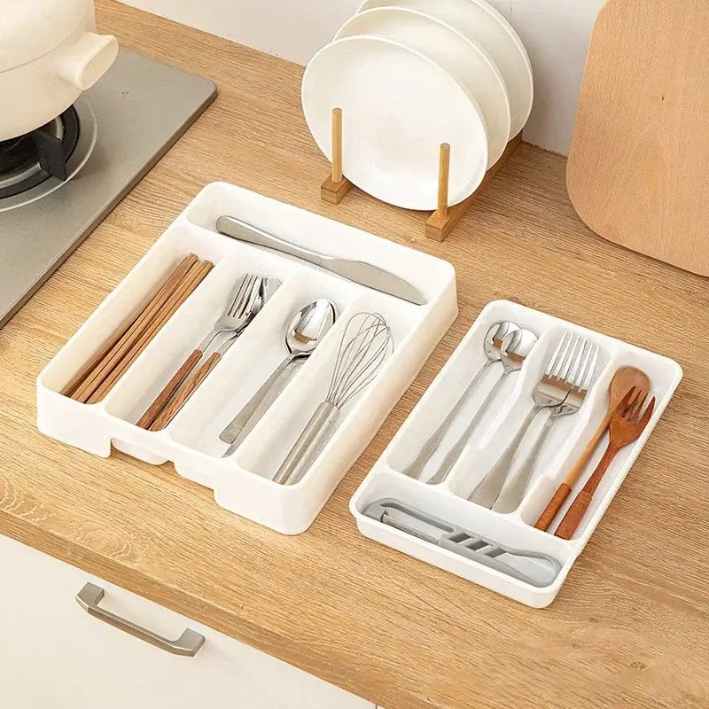 Organisateur de tiroir à couverts en plastique blanc, avec des compartiments segmentés contenant divers ustensiles pour un usage en cuisine.