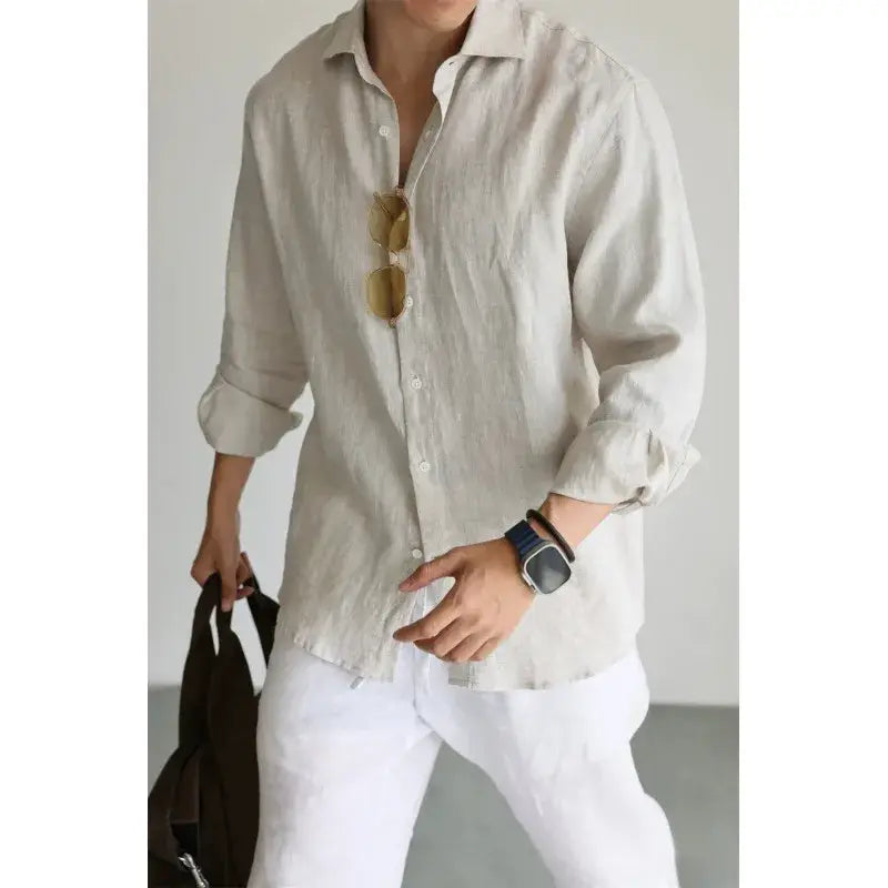 A light beige men cotton linen casual button down shirt with long sleeves rolled cuffs and a collar.