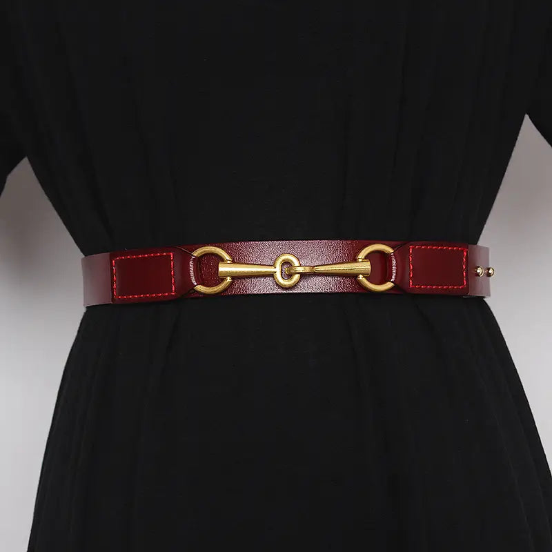 Red leather women belt with gold-tone horsebit buckle displayed on a white background.