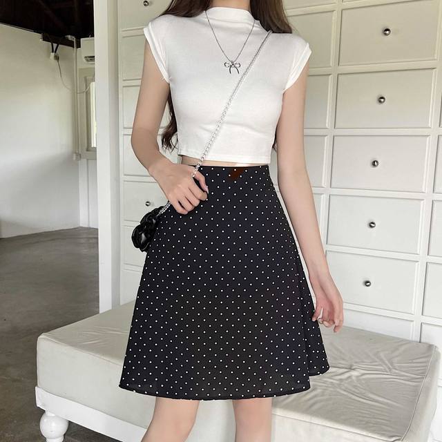 Falda negra con lunares blancos que presenta una silueta midi línea A adecuada para un look informal o formal