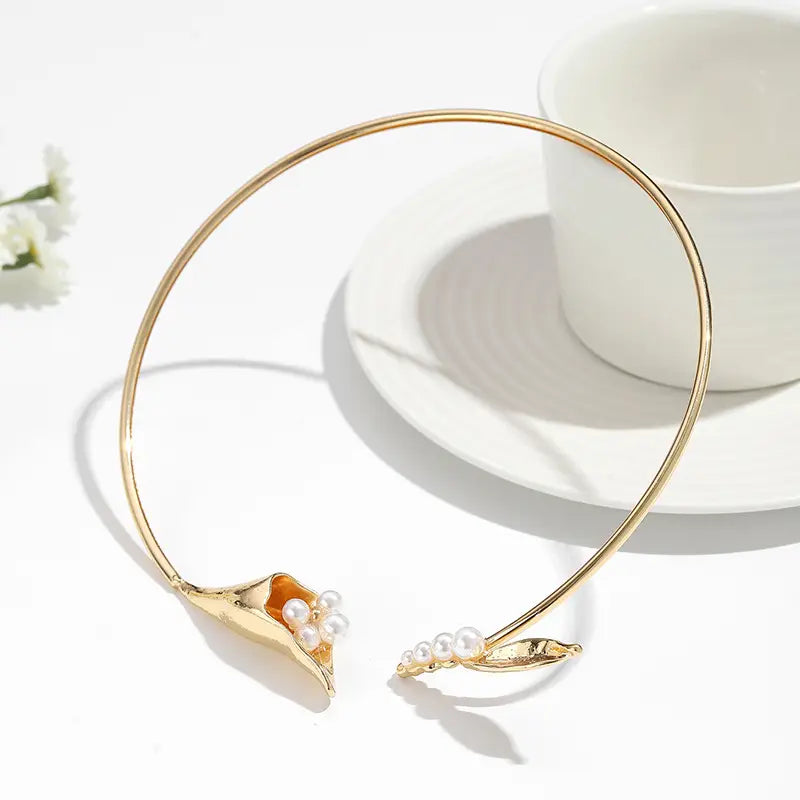 Chokerkette mit goldfarbenem Ton, florales Design mit einer zarten Calla-Lilie, eingebetteten Perlen und einem Akzentstein in Orange.