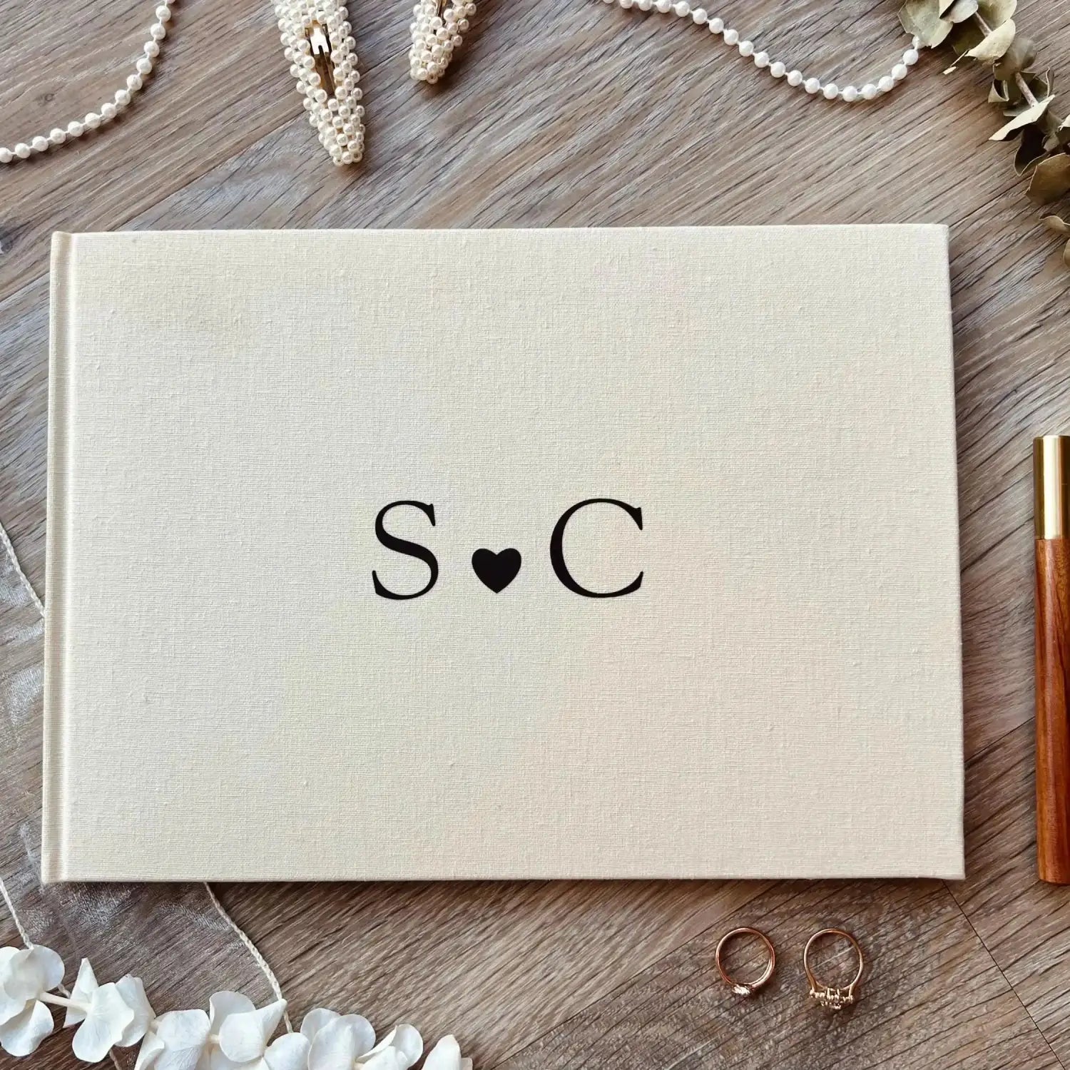 Livre d’invités de mariage en lin beige au toucher texturé, personnalisé, album Polaroid, avec des initiales monogrammées noires en forme de s cœur c sur la couverture.