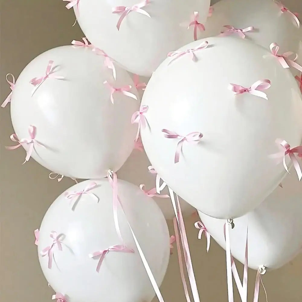 Ensemble de ballons à nœud blanc comprenant des ballons blancs ornés de délicats rubans roses, pour la décoration de fête.