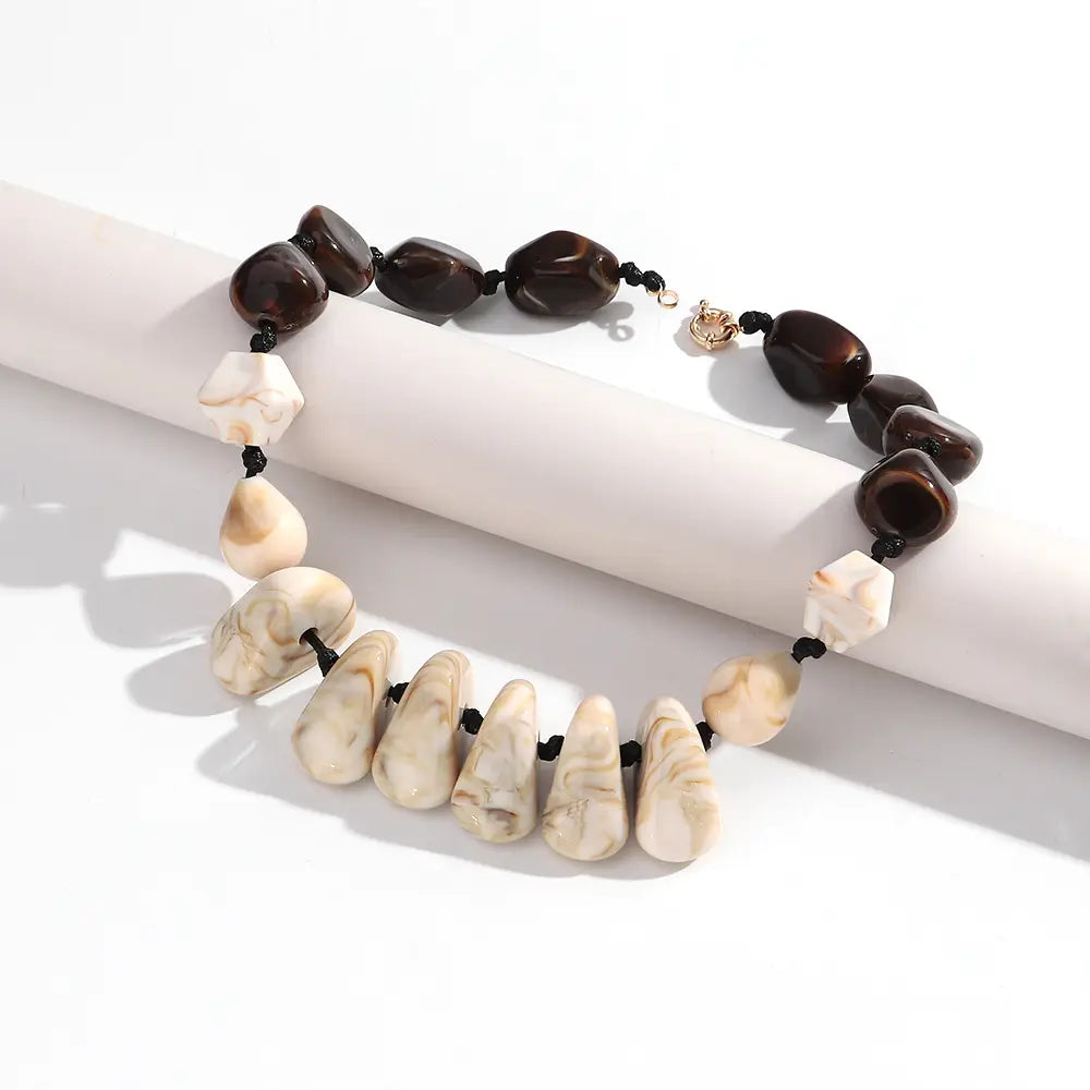 Collier ras du cou en résine à motif géométrique, fait de perles marbrées, au style élégant, avec alternance de perles en pierre brun foncé et crème, et une attache à tonalité dorée.