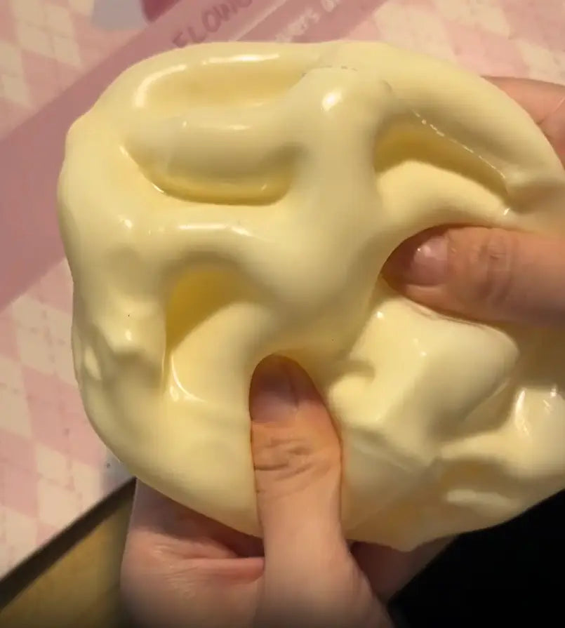 Un jouet à mâcher et à malaxer en forme de fromage jaune pâle en gelée brillante, à texture lisse et extensible, que l’on presse pour apaiser le stress lié au jouet et soulager le stress.