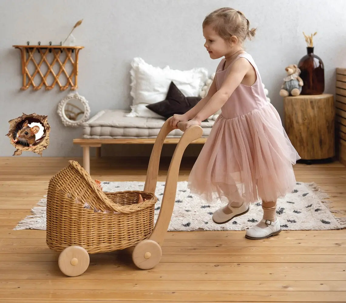 Une petite charrette pour bébé en osier tressé, avec une poignée et des roues en bois clair, représentée aux côtés d’un autocollant mural en PVC amovible pour trou de souris mignon 3D, convenant pour une décoration par autocollants de format.