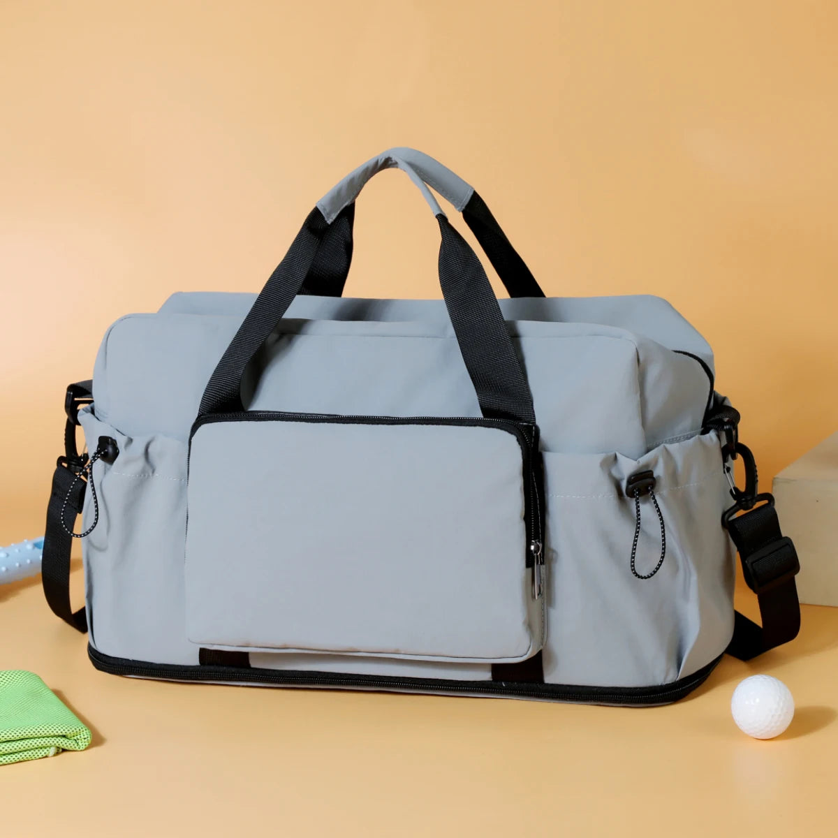 Sac de voyage duffel léger gris clair extensible avec poignées et bordures noires, doté de plusieurs compartiments zippés.