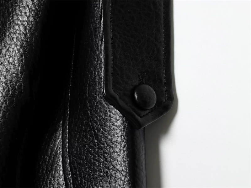 黒のフェイクレザーボンバージャケット。マット仕上げの金属ボタンディテール付きの黒いレザーストラップを特徴としています