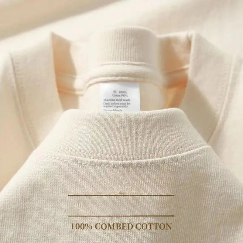 Una camiseta de algodón suave color blanco roto con cuello redondo, confeccionada en 100 % algodón peinado, con un sutil canaleteado en el cuello, destacada en un producto de camiseta de algodón de cuello redondo color azul marino.