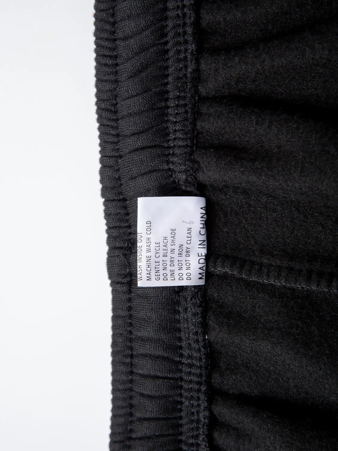 Joggers en polaire noirs, avec une taille élastique et une étiquette d’entretien blanche cousue à l’intérieur de la taille, conçus pour une tenue d’hiver décontractée.