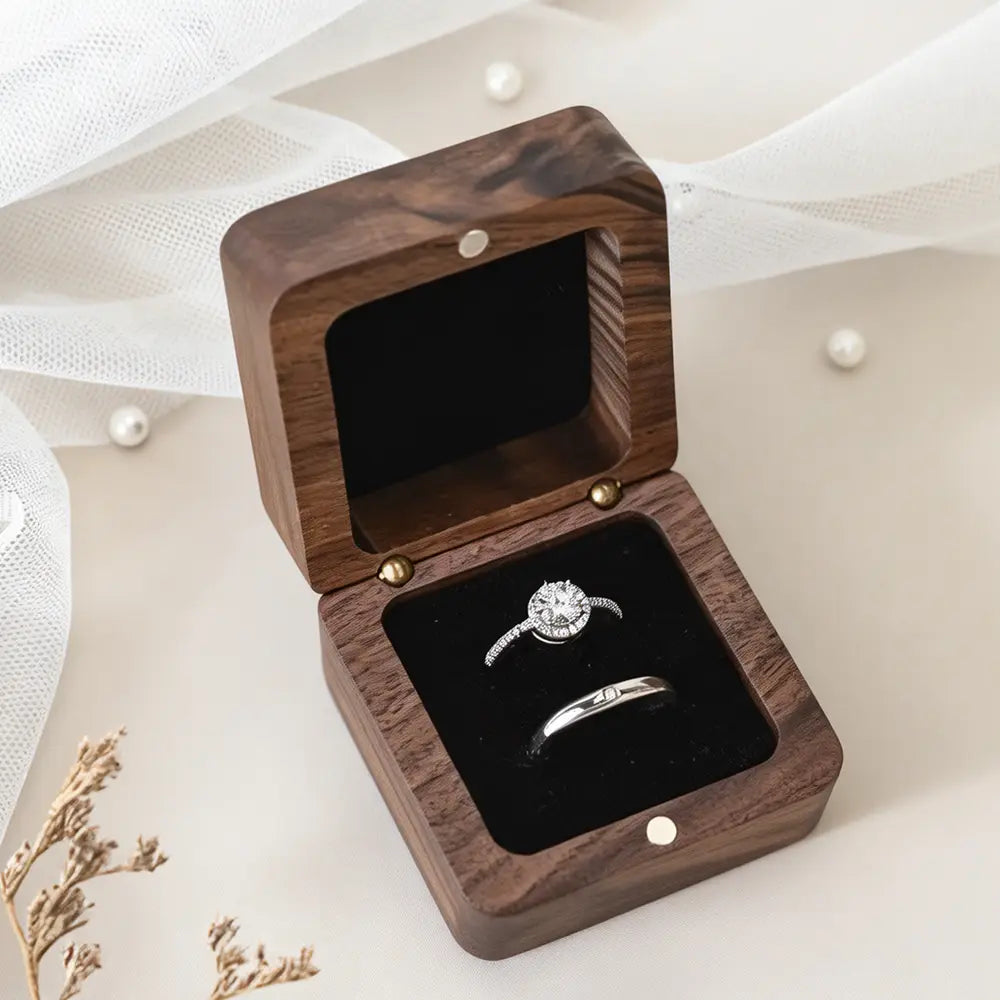 Dark wood personalized wooden wedding ring box with black velvet interior holding a diamond solitaire and wedding band.