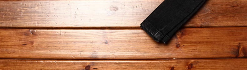 a black leather wallet resting on a wooden surface accompanying mens slim fit printed black denim jeans product.