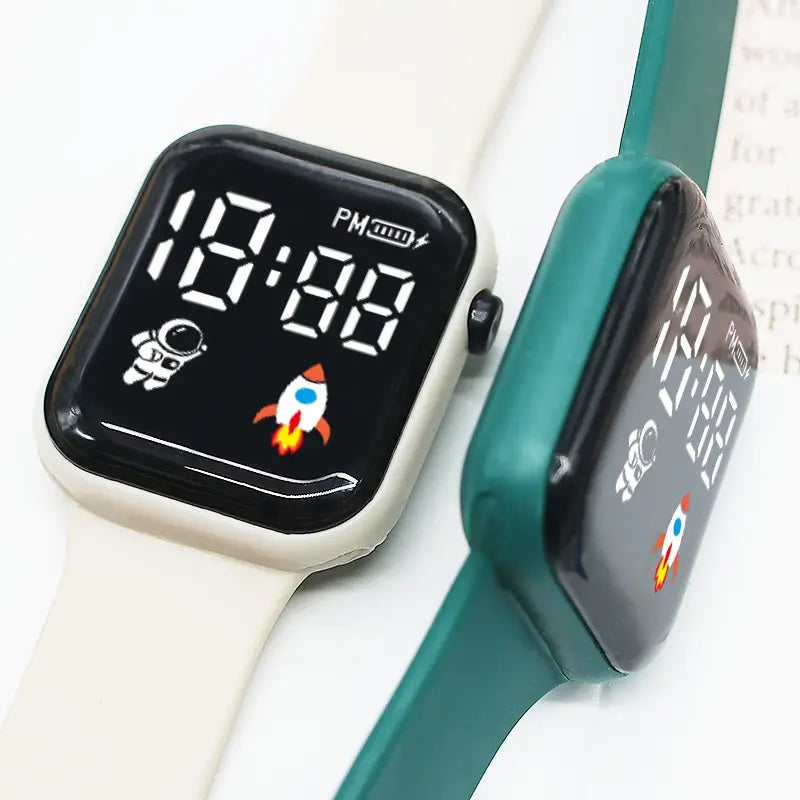 Deux montres électroniques pour enfants, avec affichages numériques LED à thème spatial : une montre avec écran noir et bracelet blanc cassé, et l’autre avec écran noir, boîtier et bracelet turquoise, conçue pour un usage sportif garçons et filles.