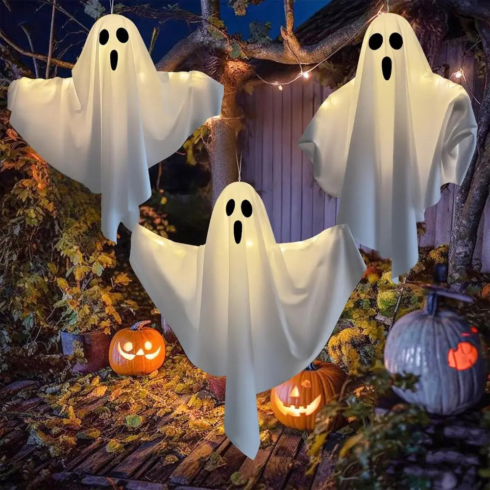 three glowing white inflatable halloween ghost lights with black eyes and wide mouth cutouts hanging outdoors as ghost pathway lights for outdoor decor
