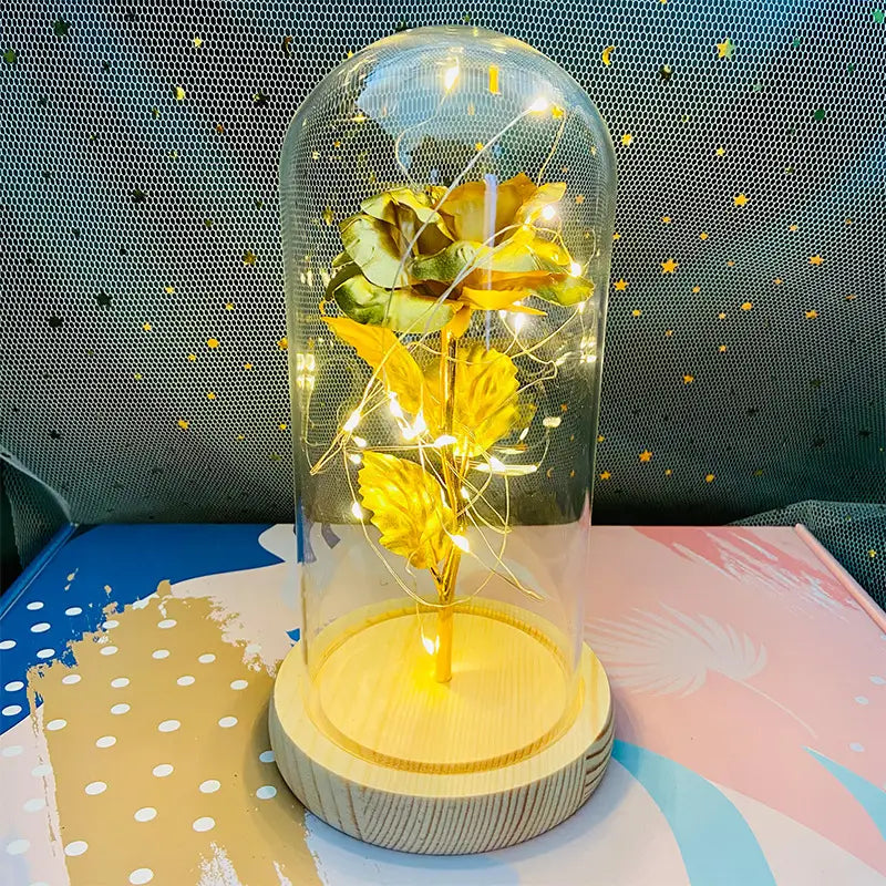 Geschenk „Eternal Gold Rose Glass Dome LED Light“, mit einer goldenen Rose mit zarten Blättern, umschlossen in einer klaren Glaskuppel, beleuchtet von warmen Feenlichtern.