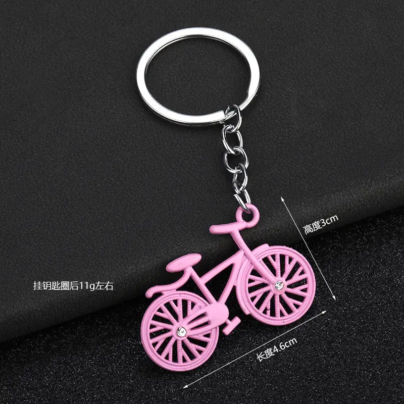 pink bicycle keychain charm set featuring a silver metal ring and chain with crystal accents on the wheels