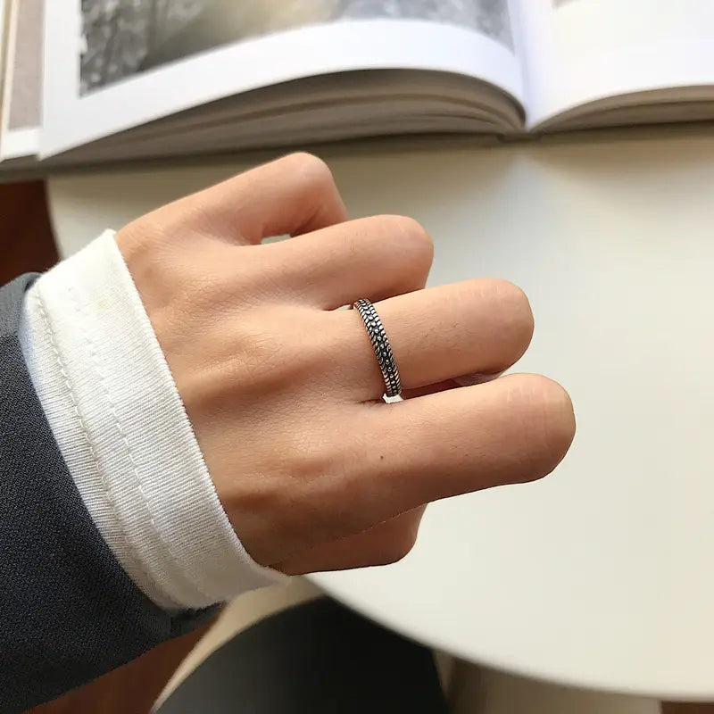 Un anillo delicado para el dedo del pie trenzado de plata de ley con un diseño texturizado adorna el dedo.